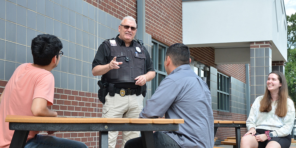 Campus police officer talking to students in the courtyard.
