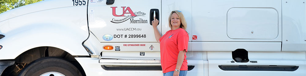Female student proudly standing outside of UACCM truck with her hand on door handle.