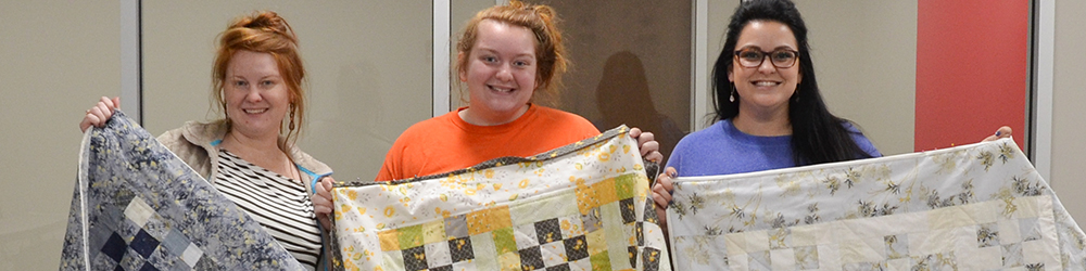 Community education class participants displaying the quilts they made in class.